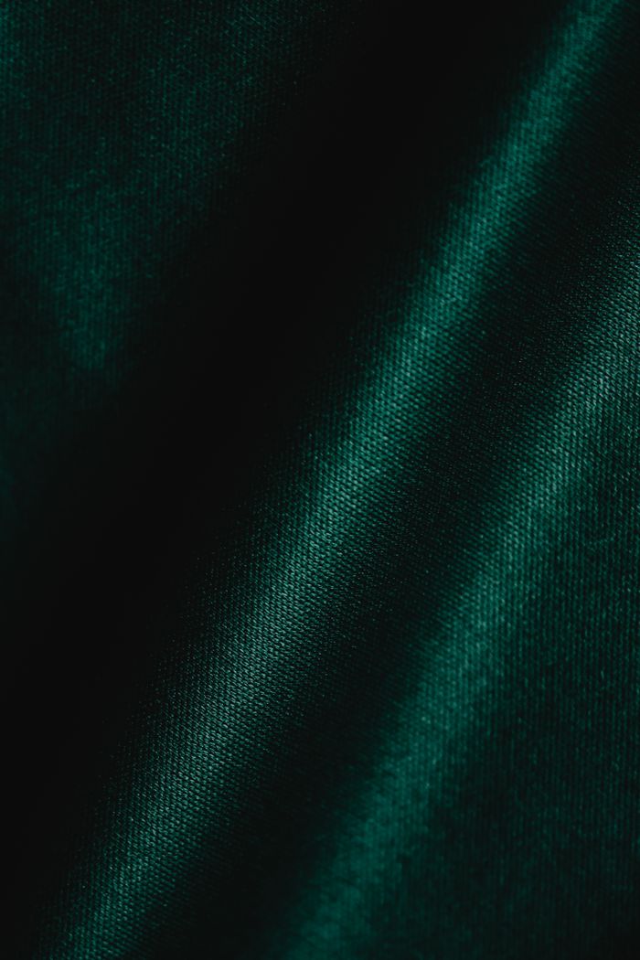 Detailed close-up shot of textured green fabric with shadows, emphasizing the material's creases and folds.